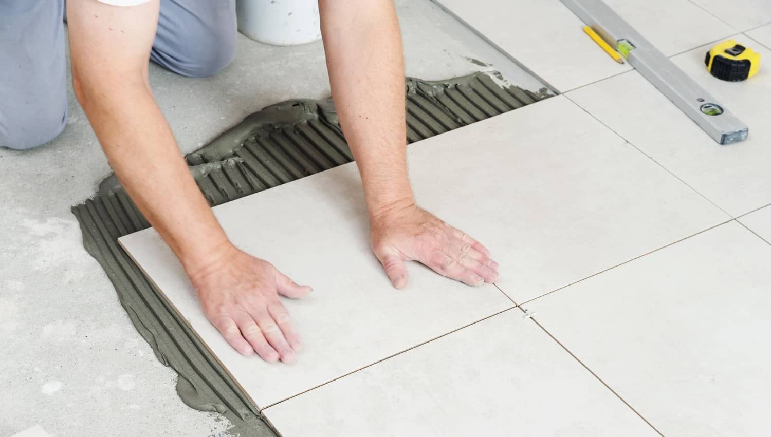 hands-worker-are-pressing-ceramic-tile-floor